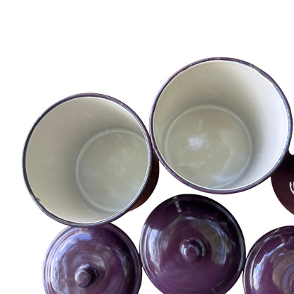 Close-up of enamel canister lids showing reflective glaze and fitted knobs