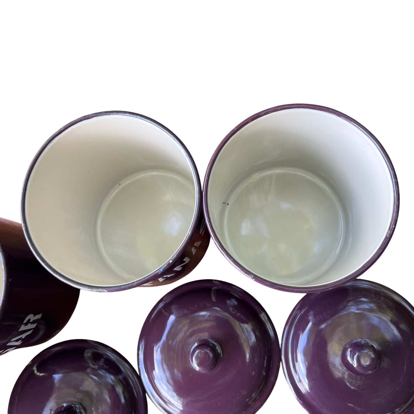 Canisters arranged in a line on a vintage wooden table, purple enamel finish