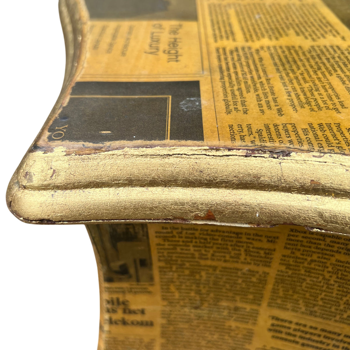 Detail of peeling newspaper collage at the edge of a vintage bedside cabinet