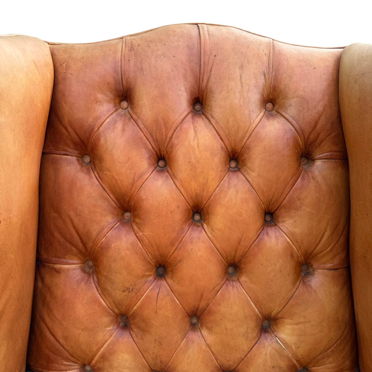 Detail of decorative brass‑coloured studding running down the wing of the leather armchair