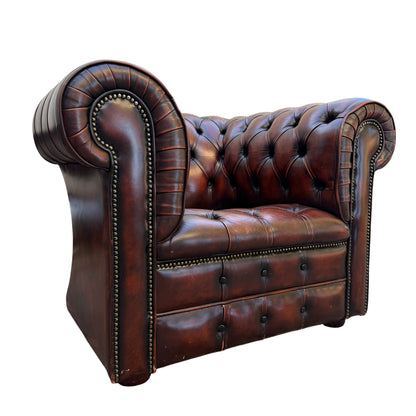 Chesterfield leather armchair in brown with deep button tufting and brass stud trim, front corner view