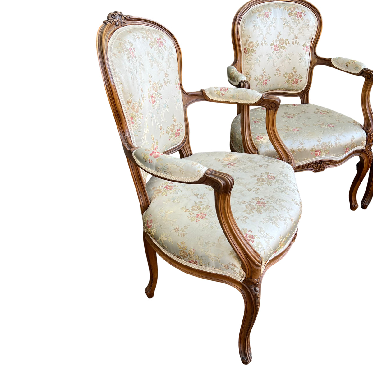 Close-up of a vintage carved walnut bergère armchair showing floral upholstered back and carved crest rail