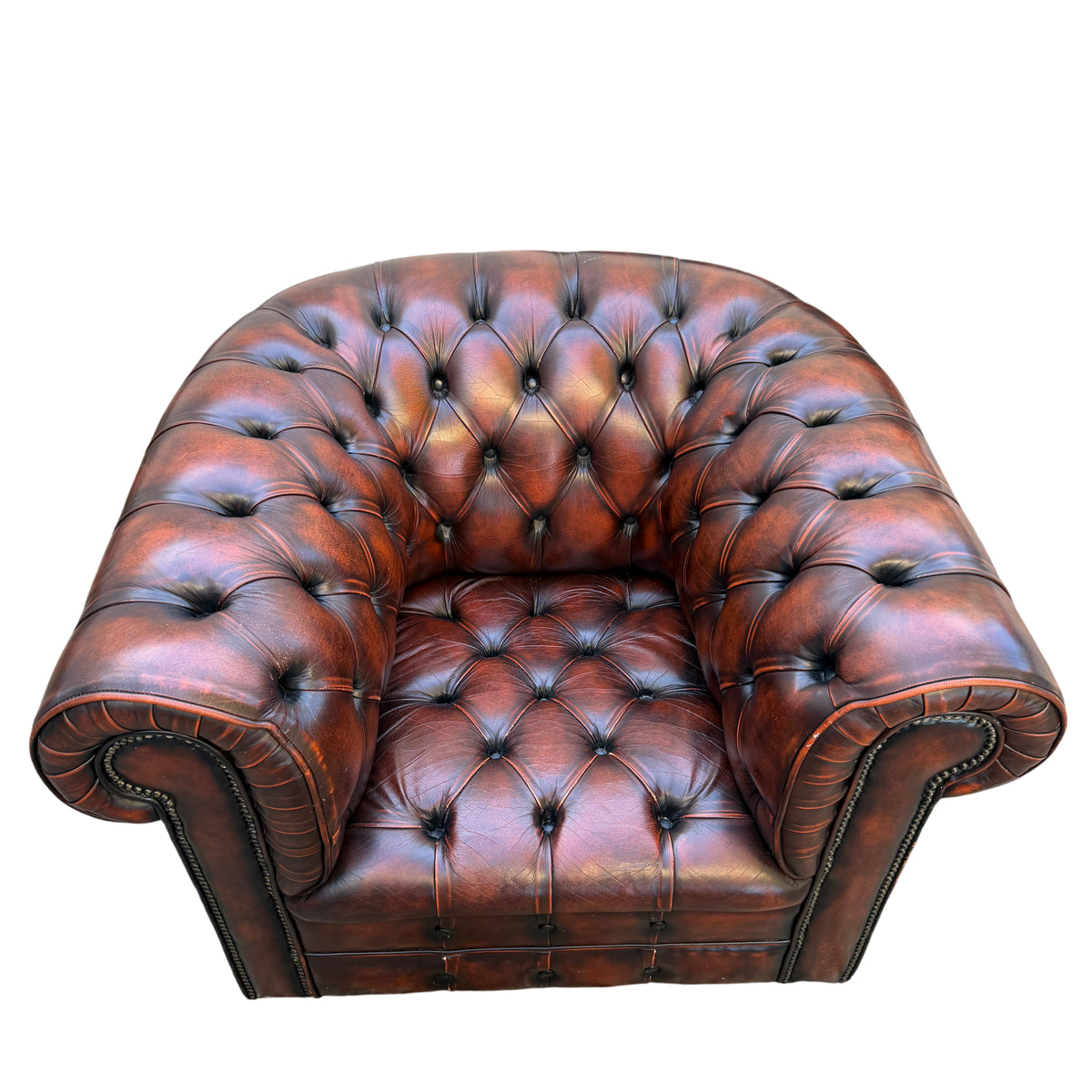 Close-up of rolled arm with brass studs and pleated leather detail on Chesterfield armchair