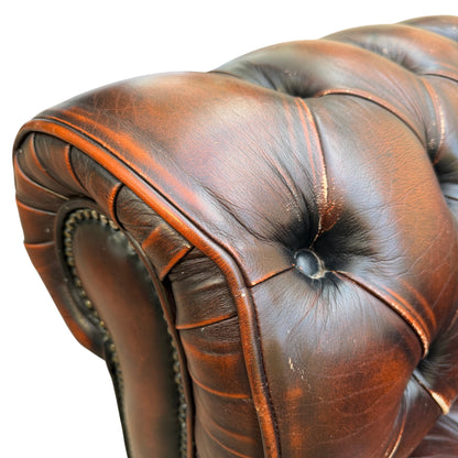 Lower front panel and stud trim on a brown leather Chesterfield armchair