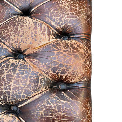 Full-width view of distressed brown leather Chesterfield sofa outdoors