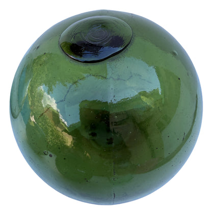 Olive green glass fishing float with a long stable crack visible across the body