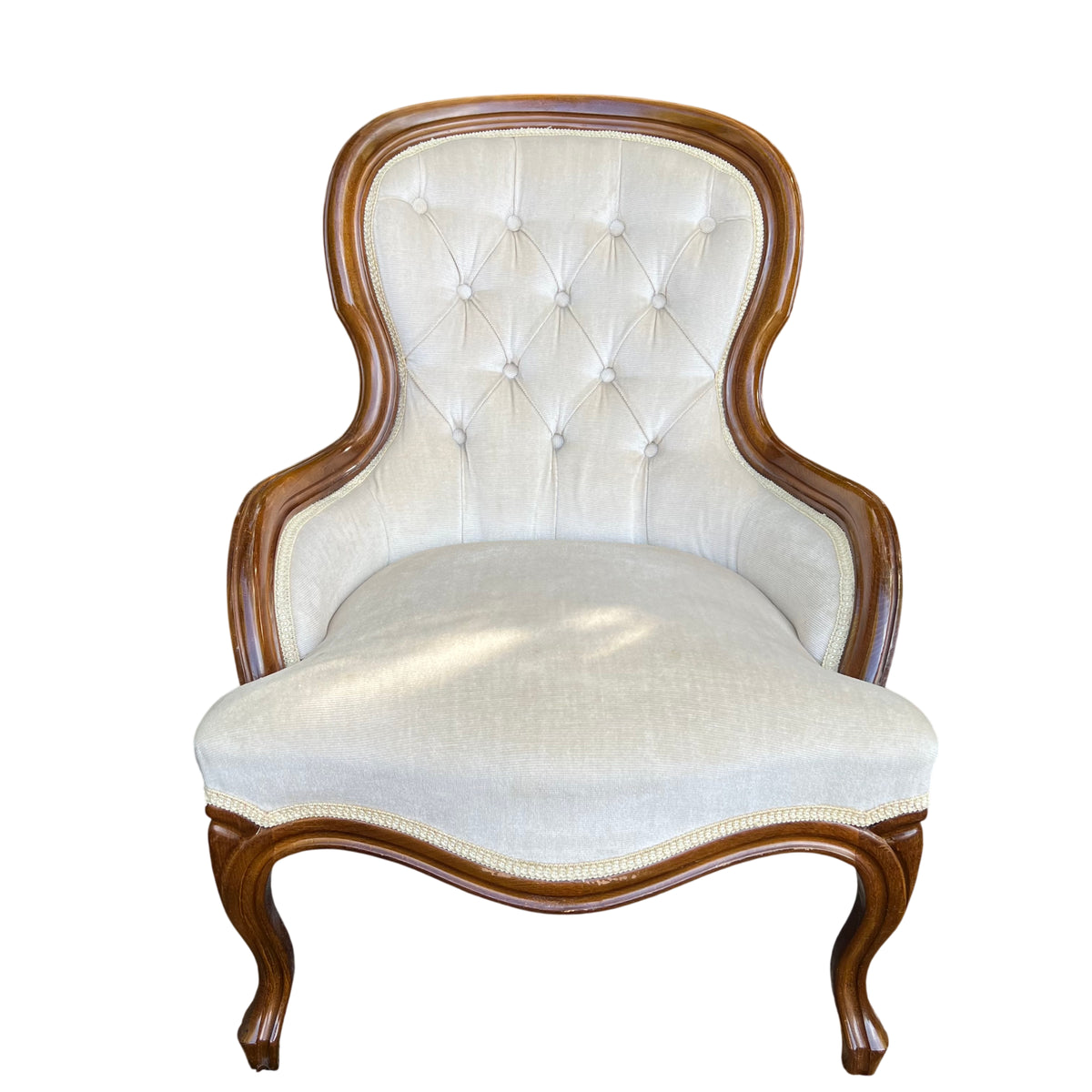 Victorian button-back upholstered armchair with shaped wood frame and cream fabric
