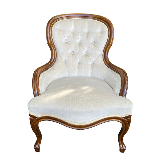 Victorian button-back upholstered armchair with shaped wood frame and cream fabric