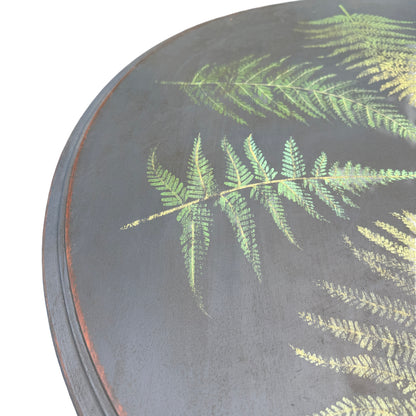 Carved apron and scrolled detailing beneath a painted round top on a vintage side table