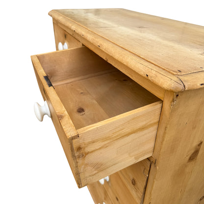 Full-height view of pine chest of drawers standing on turned feet