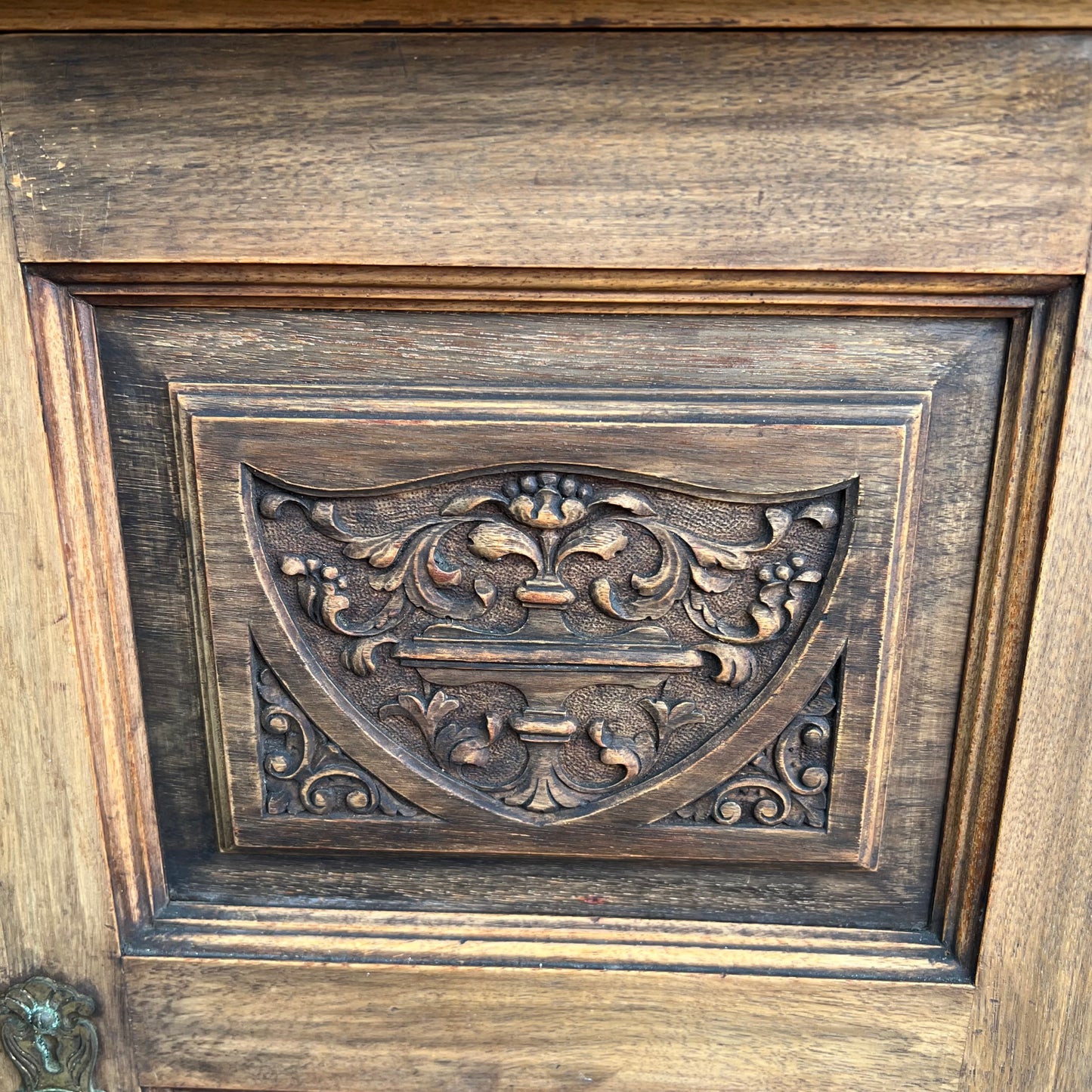 Angled view of vintage bedside cabinet showing moulded top and carved door