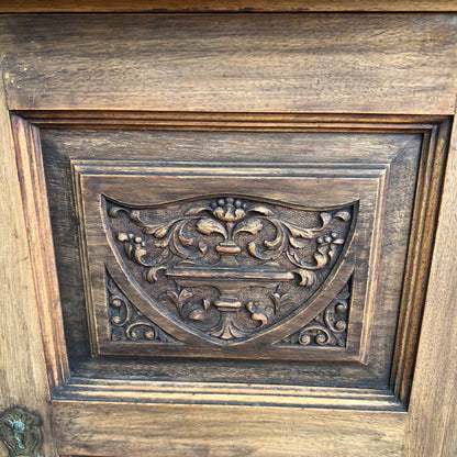 Angled view of vintage bedside cabinet showing moulded top and carved door