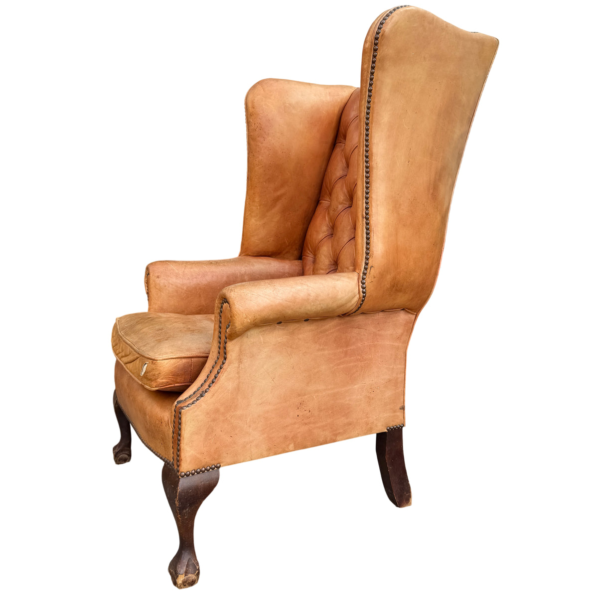 Side panel of a tan leather wingback armchair showing creasing and surface scuffs