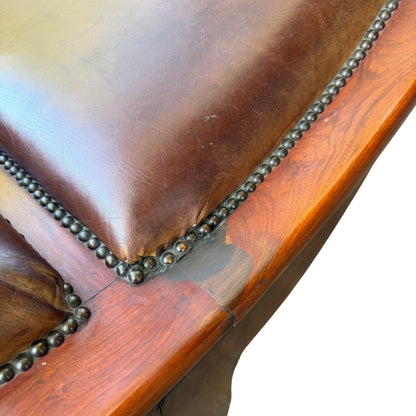 Close-up of original French leather upholstery and wooden scroll detail on chaise longue