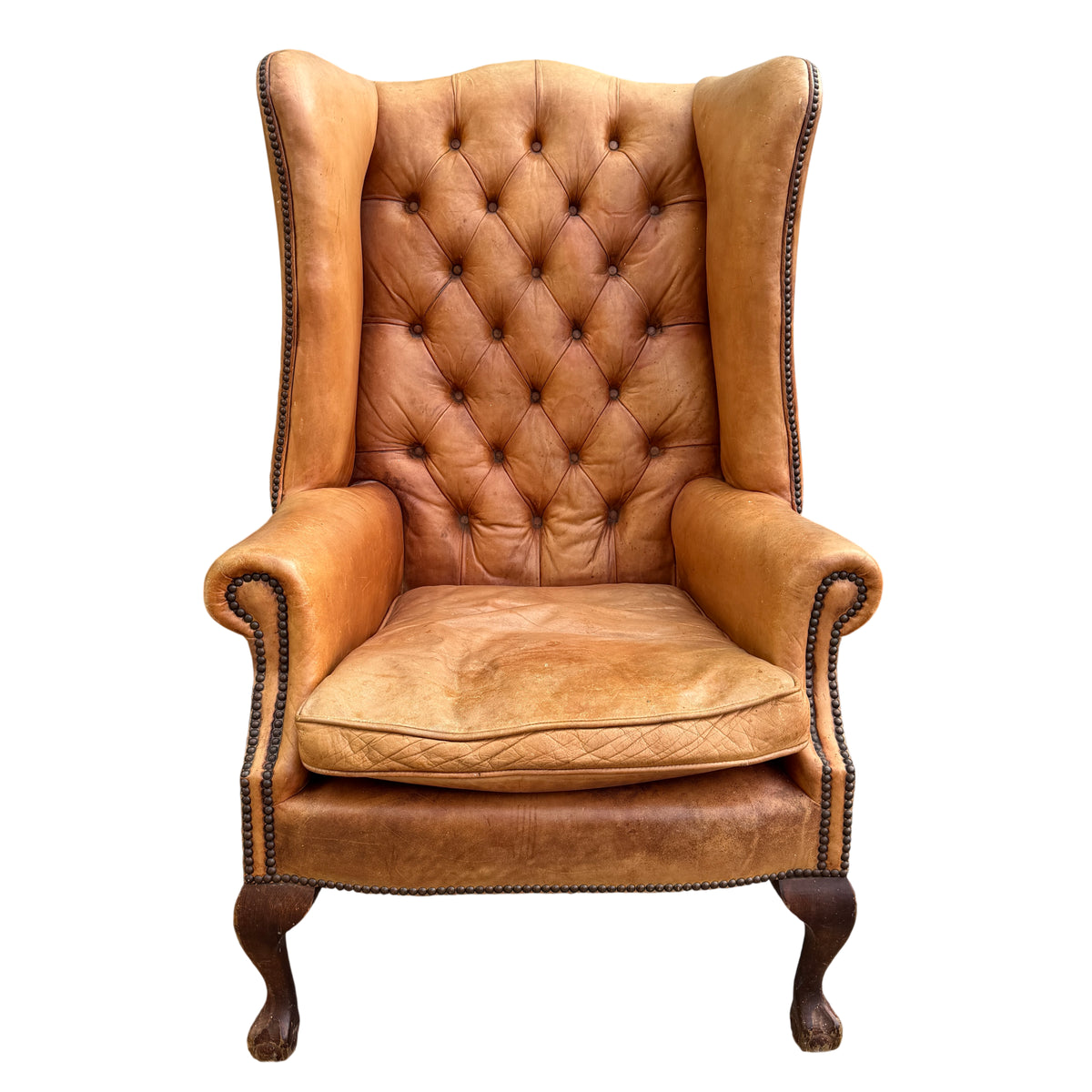 Front view of vintage tan leather wingback armchair with removable seat cushion and rolled arms