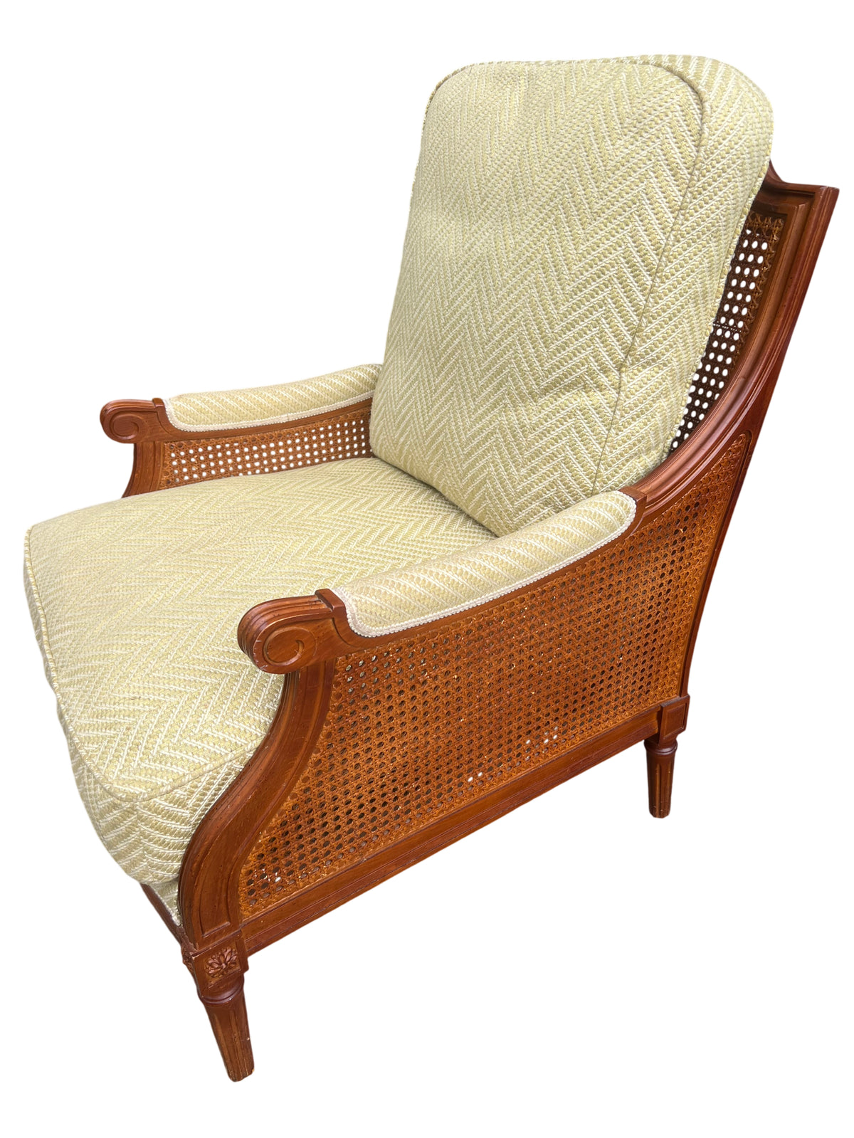 Side view of vintage cane and carved wood armchair with yellow upholstery