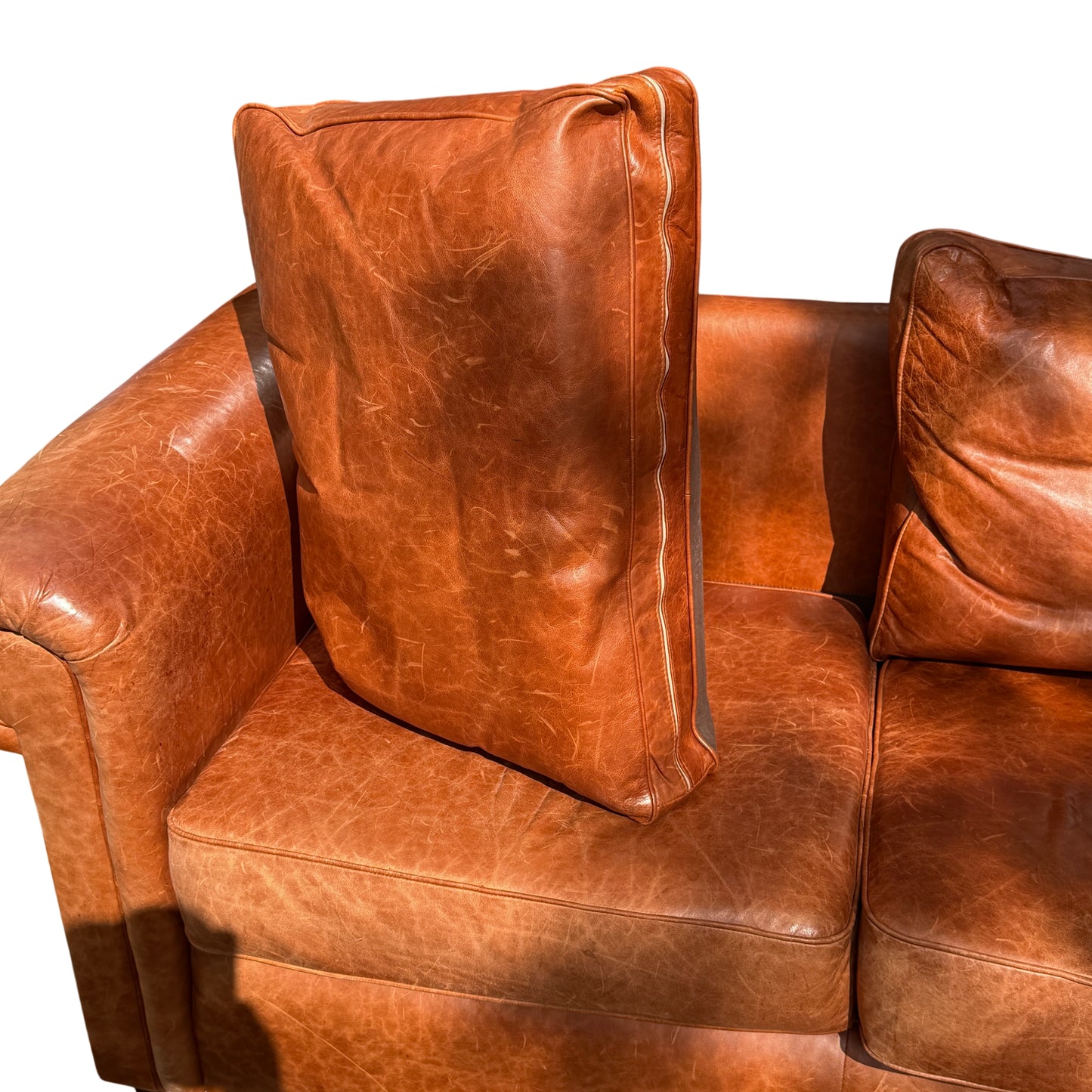 Wesley-Barrell cognac leather sofa on pavement with autumn leaves beneath