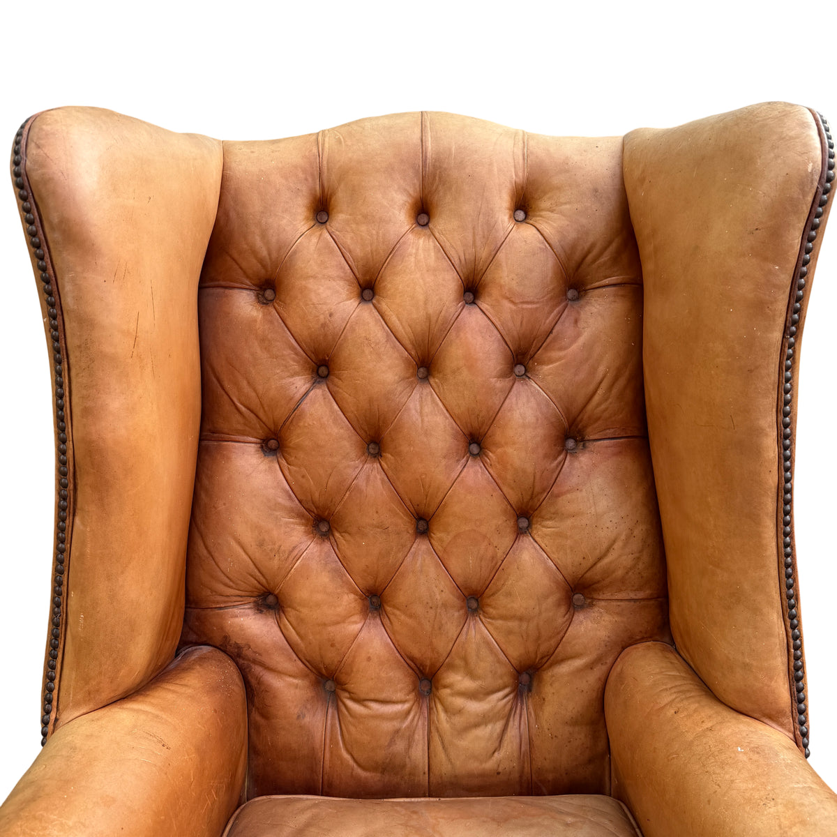 Detail of rolled arm and decorative stud trim on vintage leather wingback chair