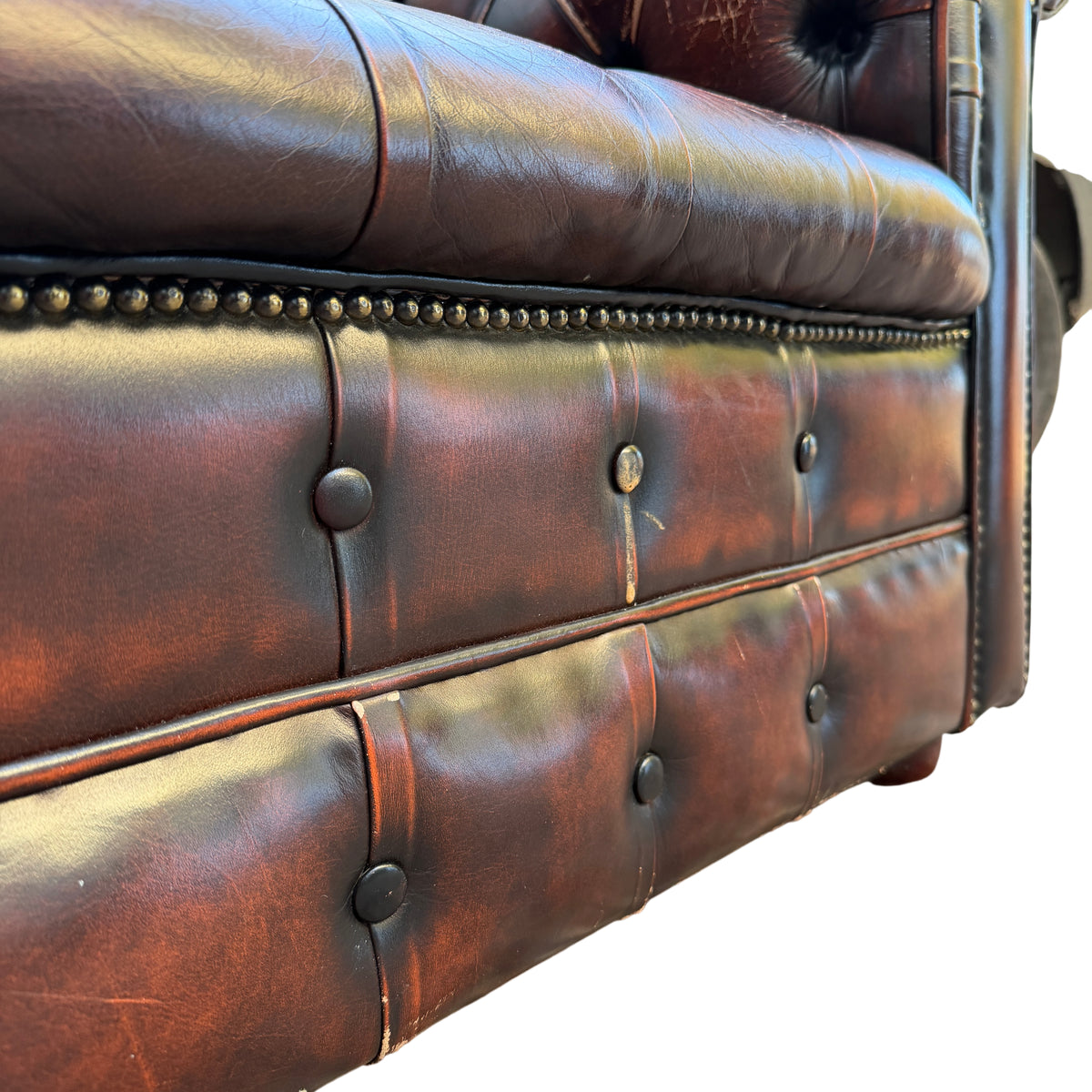Close-up of deep button tufting and aged leather patina on Chesterfield armchair