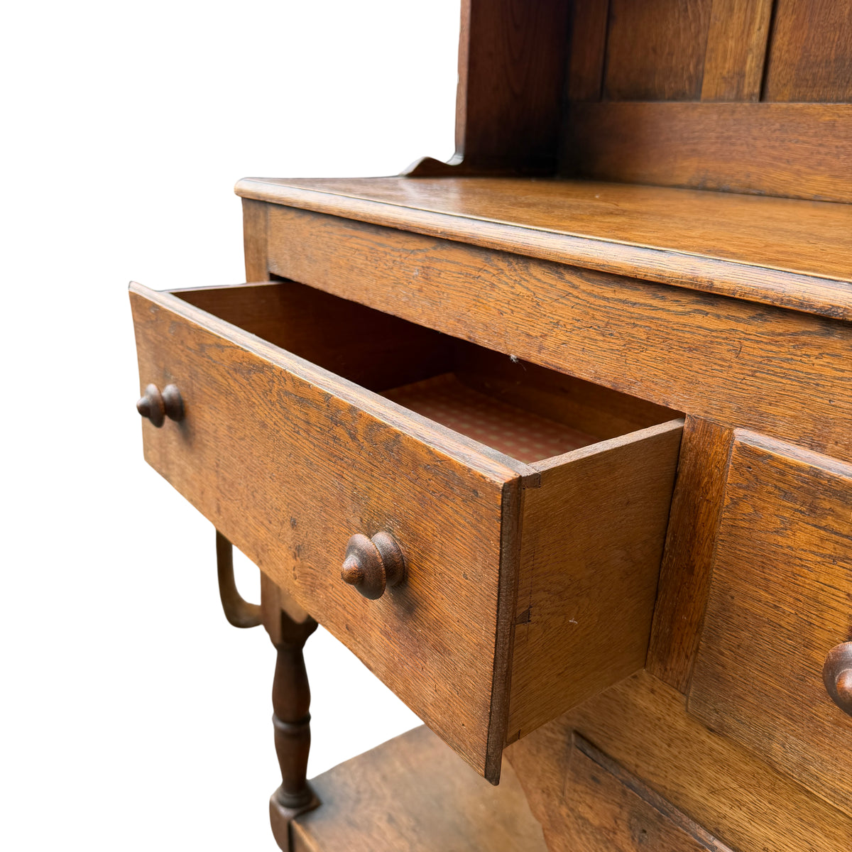 Full-length oak dresser showing turned legs, lower shelf and bun feet