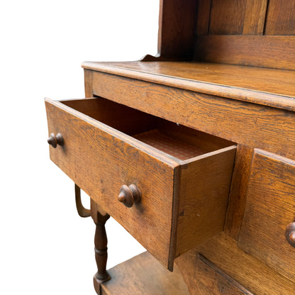 Full-length oak dresser showing turned legs, lower shelf and bun feet