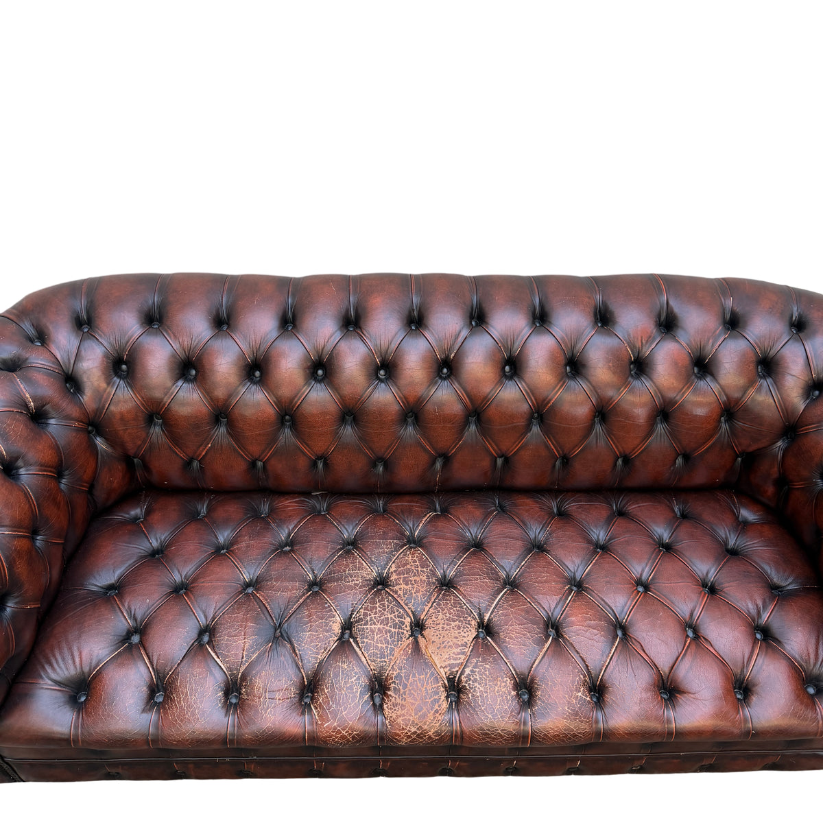 Scrolled arm of leather Chesterfield sofa with visible scuffs and wear