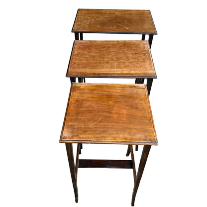 Three wooden nesting tables partially stacked showing leg repairs and wear