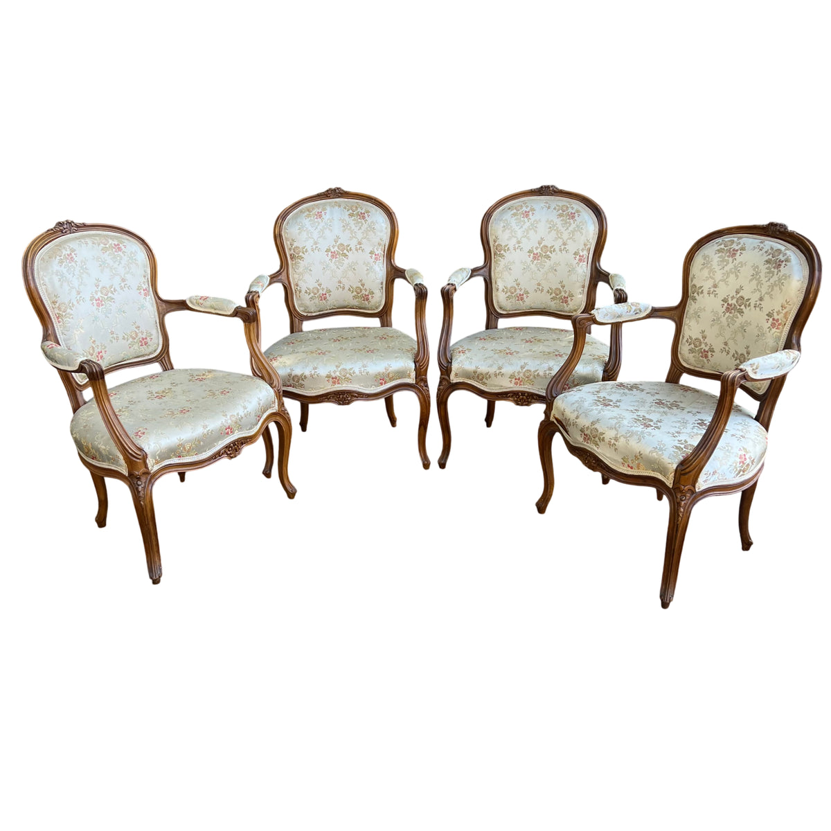 Set of vintage French-style carved walnut bergère armchairs with pale floral upholstery outdoors