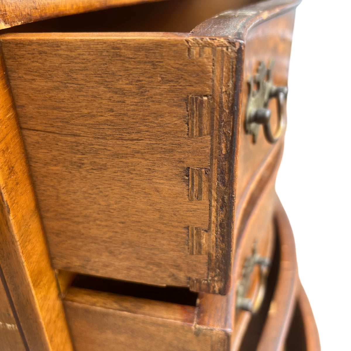 Close-up of brass drop handle and burr walnut veneer drawer front