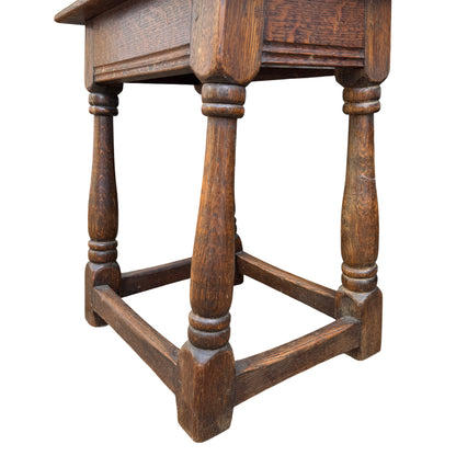 Front view of small oak side table with carved apron and turned legs