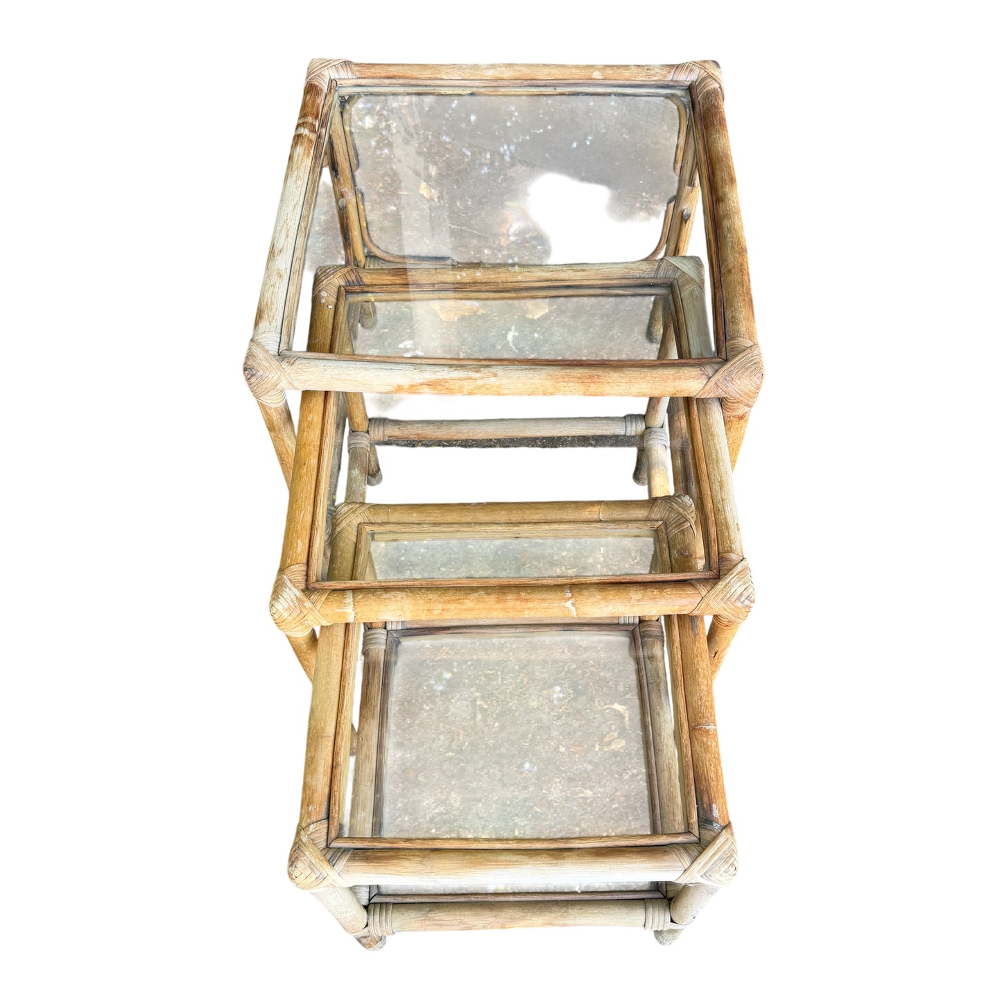 Three-piece cane nesting tables set with glass surfaces and sun-bleached rattan frames