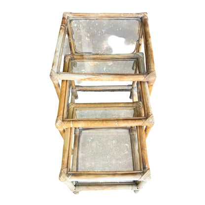 Three-piece cane nesting tables set with glass surfaces and sun-bleached rattan frames