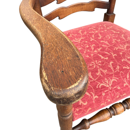 Red upholstered seat on a vintage oak dining chair with patterned fabric