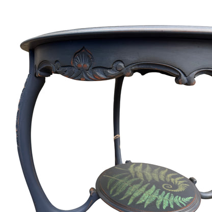 Lower shelf of round painted side table with fern motif and turned supports
