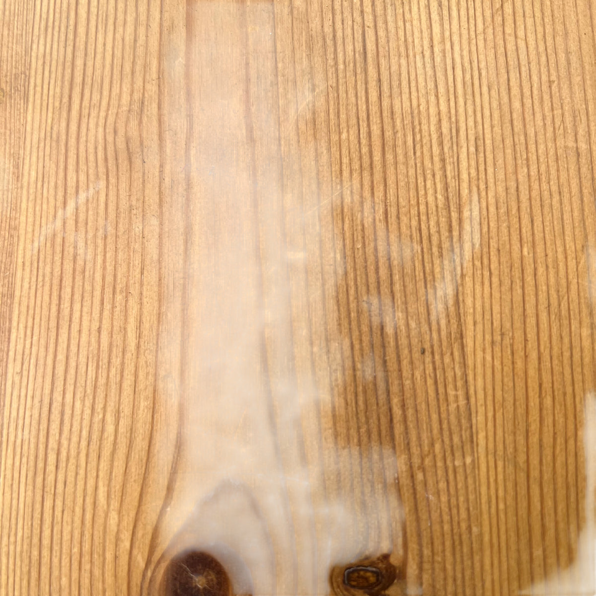 Edge detail of pine top showing wear and small chips on a vintage hall table