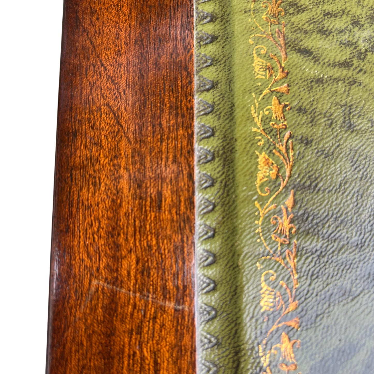 Close-up of green leather inset with gilt tooling on mahogany cabinet top