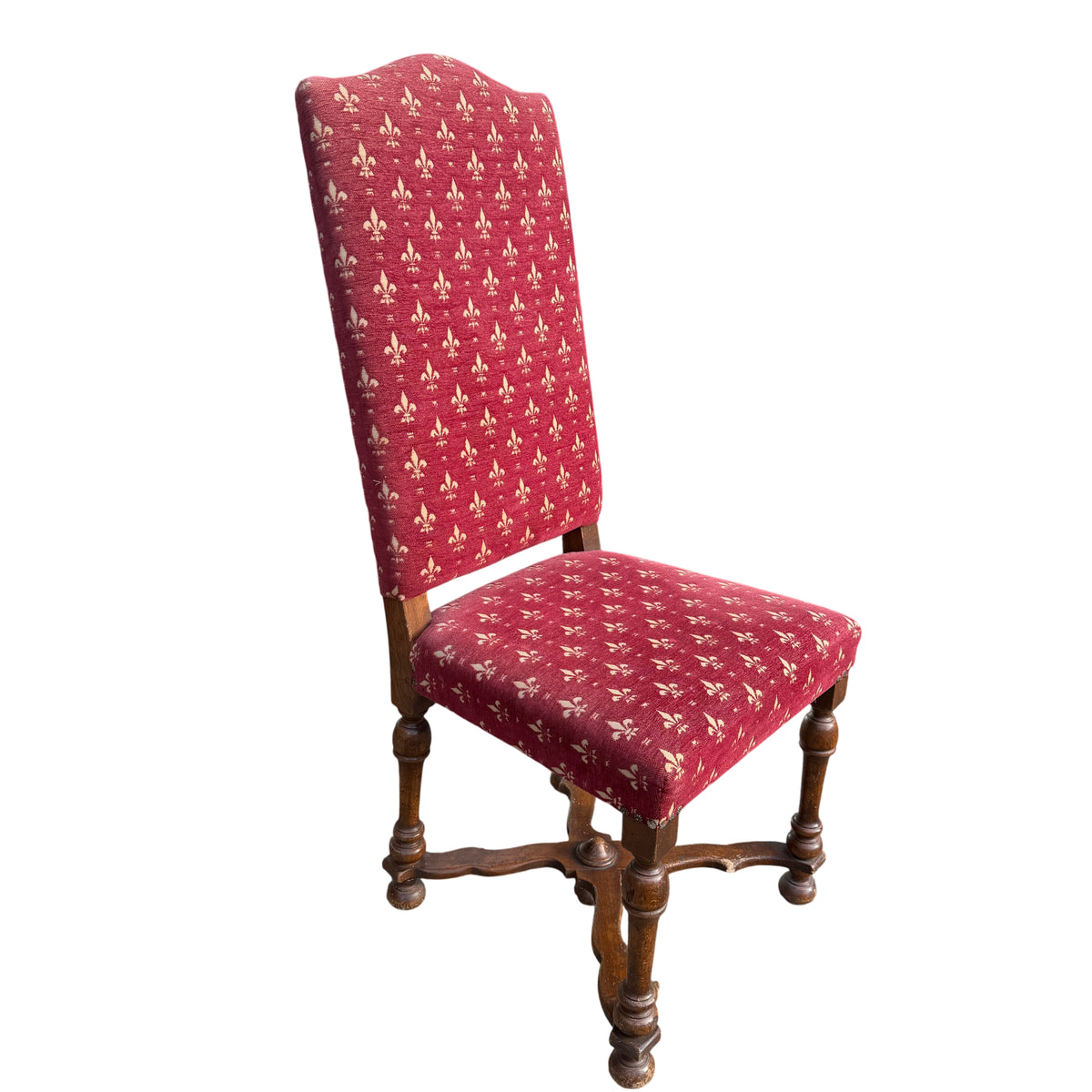 Side view of an upholstered dining chair showing turned legs and fleur de lis cloth
