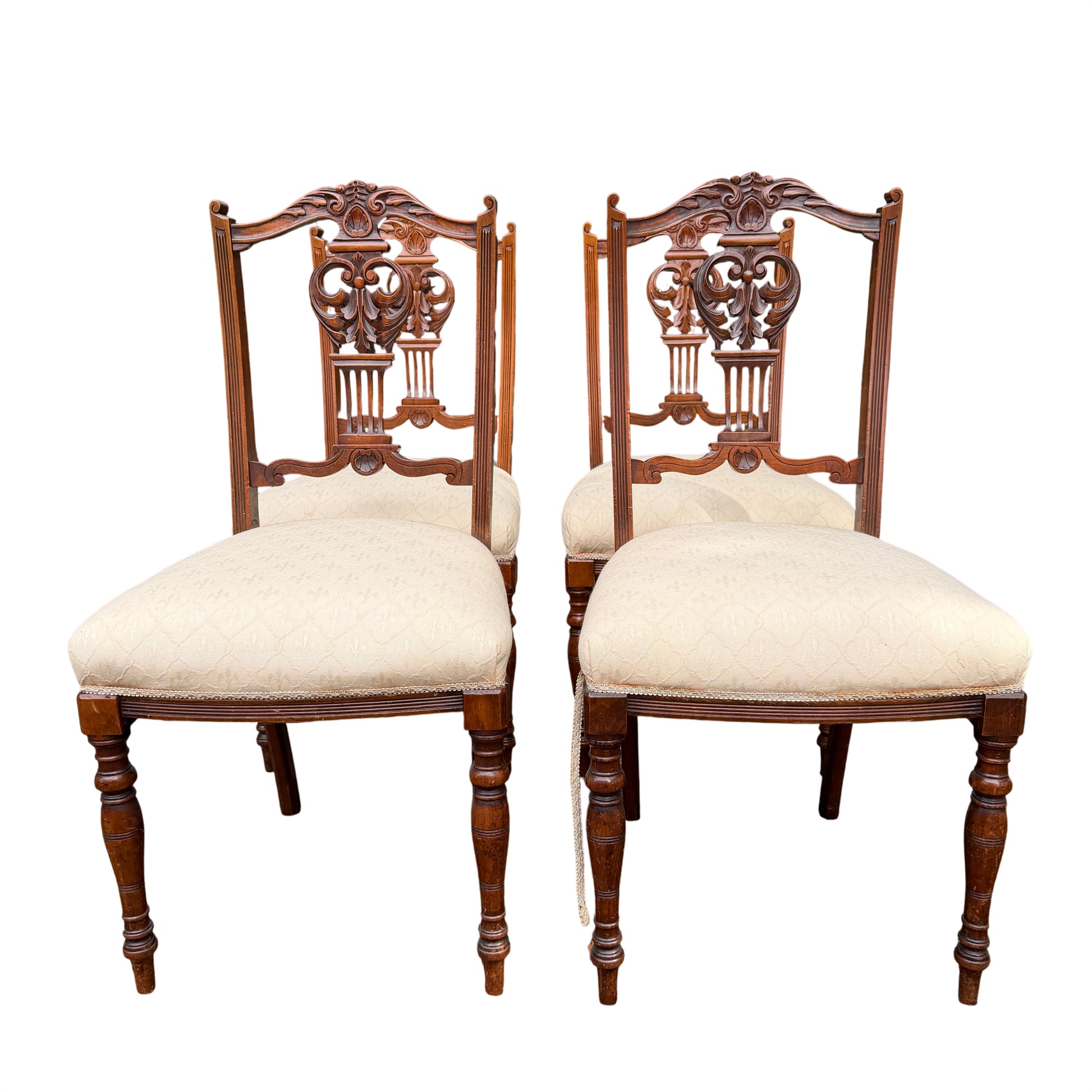 Pair of Edwardian carved dining chairs showing turned front legs and cream upholstered seats