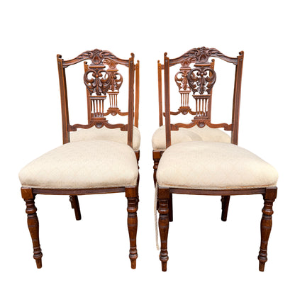 Pair of Edwardian carved dining chairs showing turned front legs and cream upholstered seats