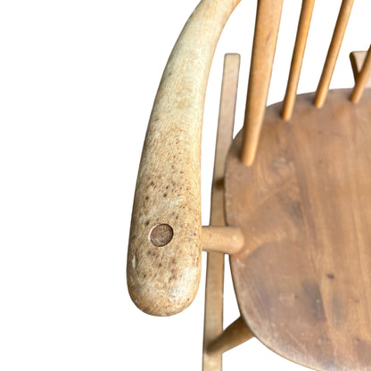 Detail of armrest and spindle joinery on a light wood vintage rocking chair