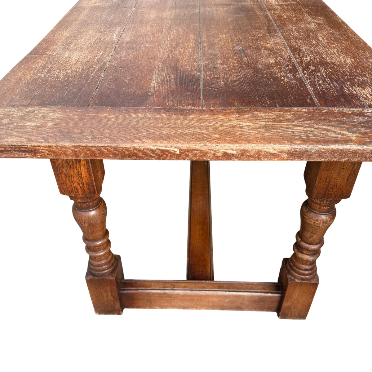 Corner of oak dining table with visible surface wear and small cracks