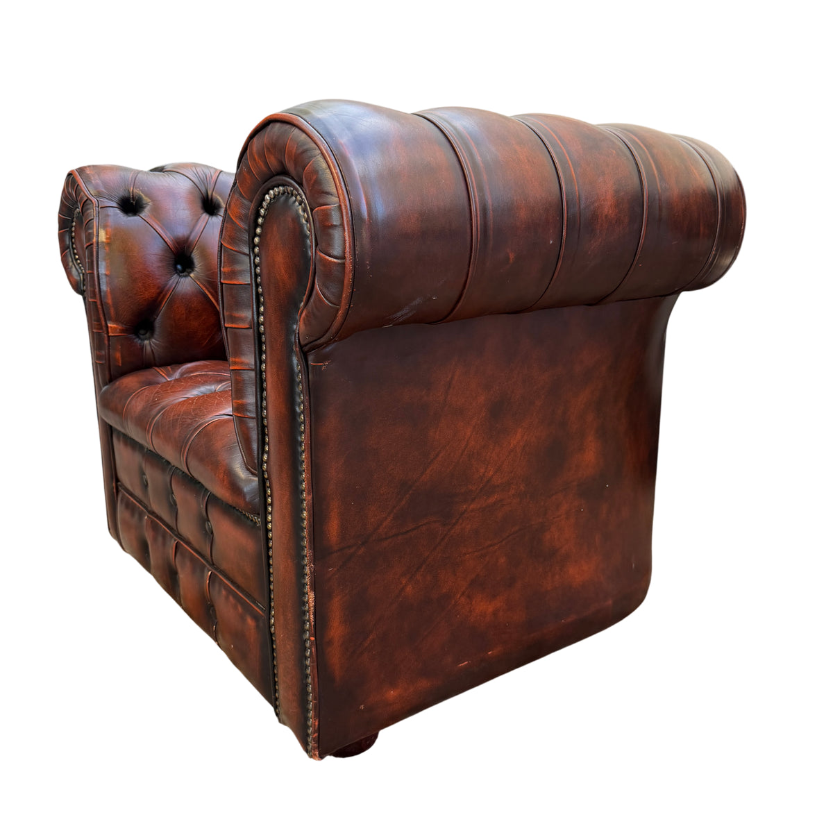 Lower front section of Chesterfield armchair showing scuffs and worn leather at the base