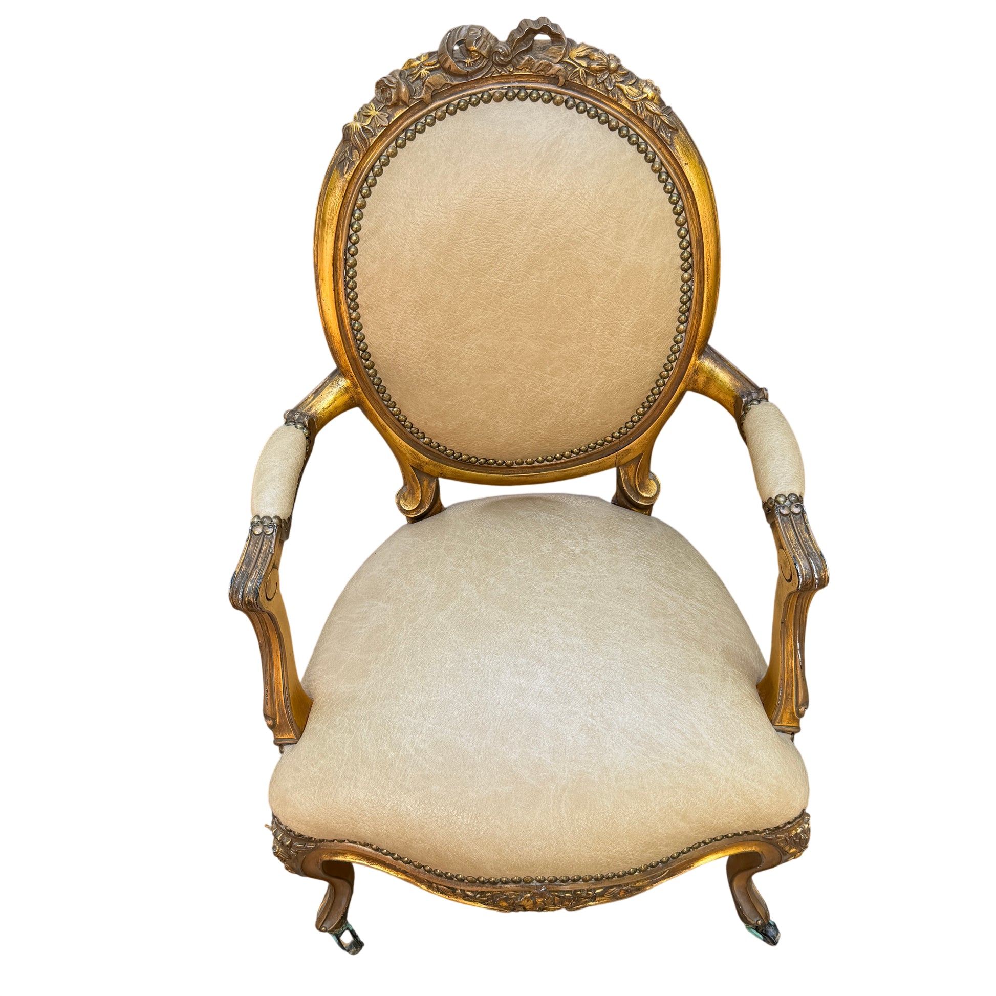 Side view of vintage gilt wooden armchair with carved arm and padded armrest in beige faux leather