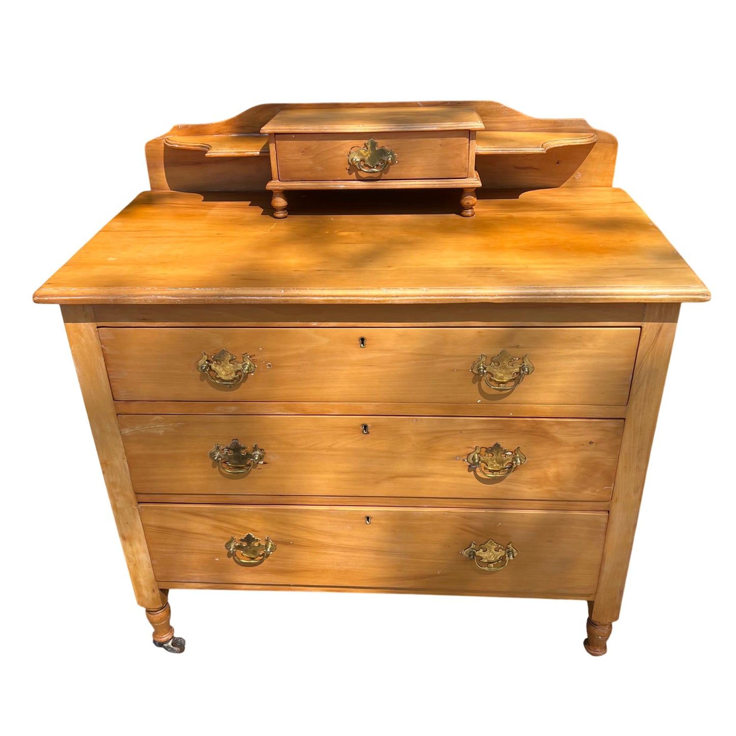 Front view of pine chest of drawers with four long drawers and brass drop handles