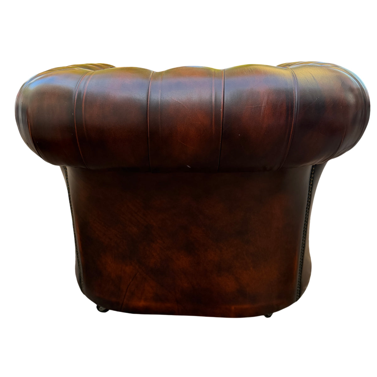 Studded trim along arm and front of brown leather Chesterfield armchair