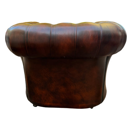 Studded trim along arm and front of brown leather Chesterfield armchair