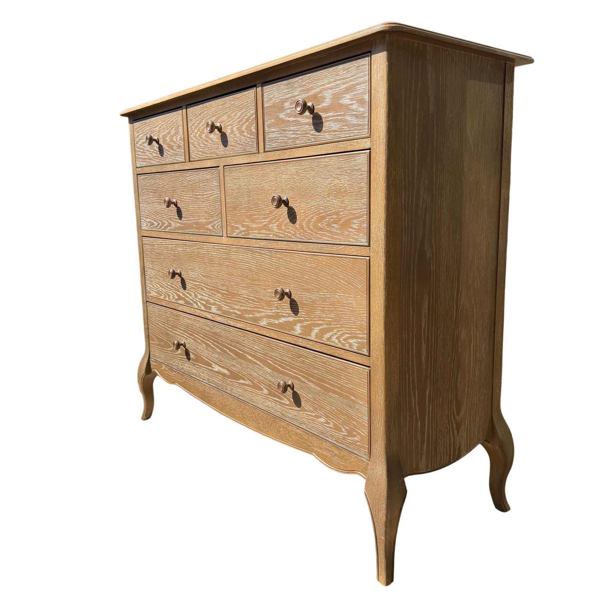 Close-up of drawer fronts showing whitewashed oak grain and round knob handles on chest of drawers