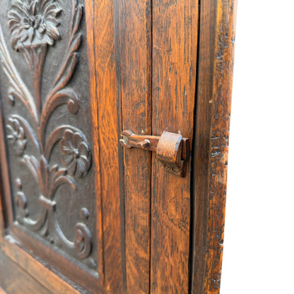 Close-up of carved flower detail on oak cabinet door