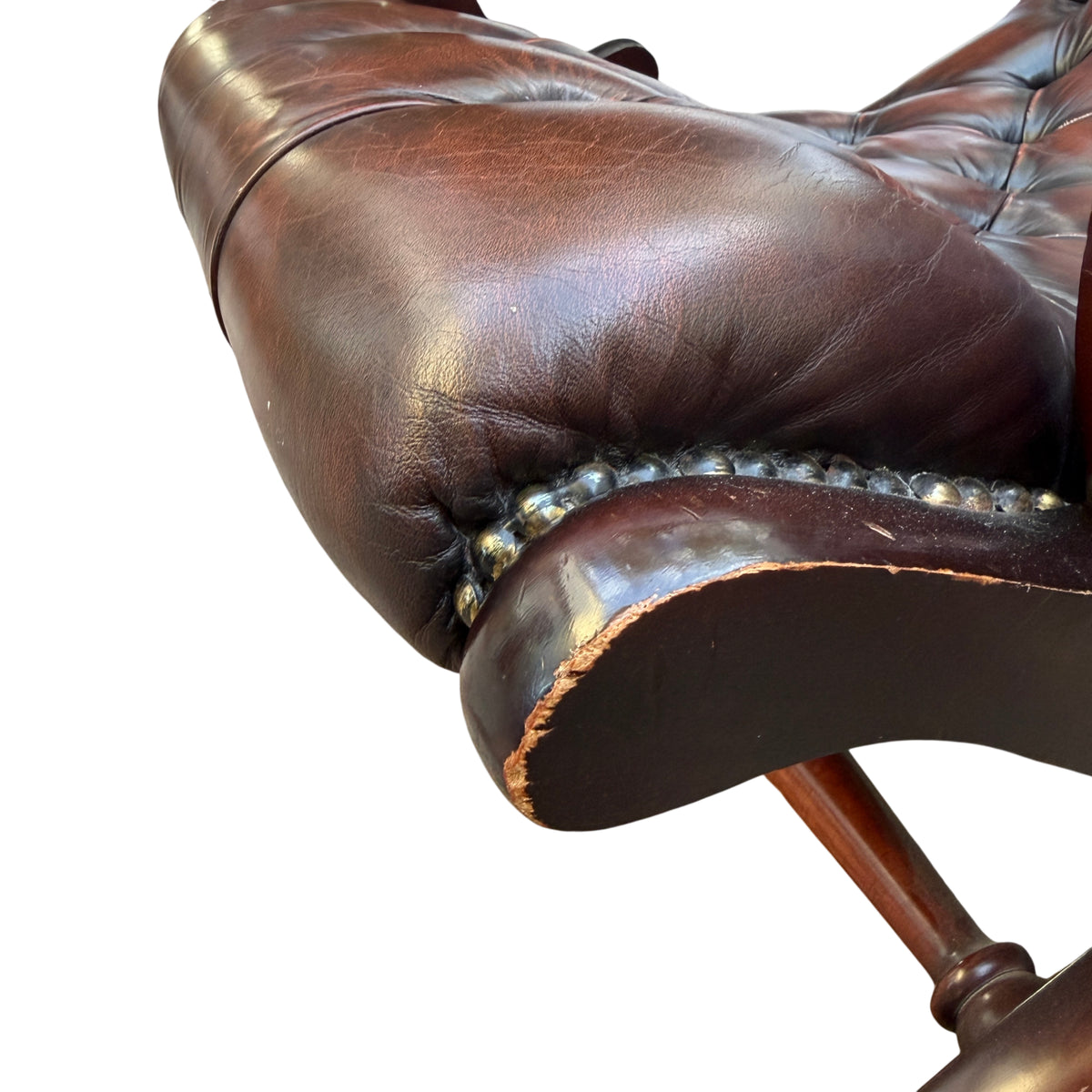 Close detail of button-tufted leather seat cushion on vintage armchair