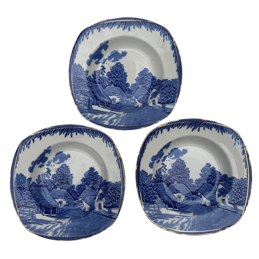 Set of three Burleigh Ware blue and white soup bowls with gilt rims and rural village transfer pattern